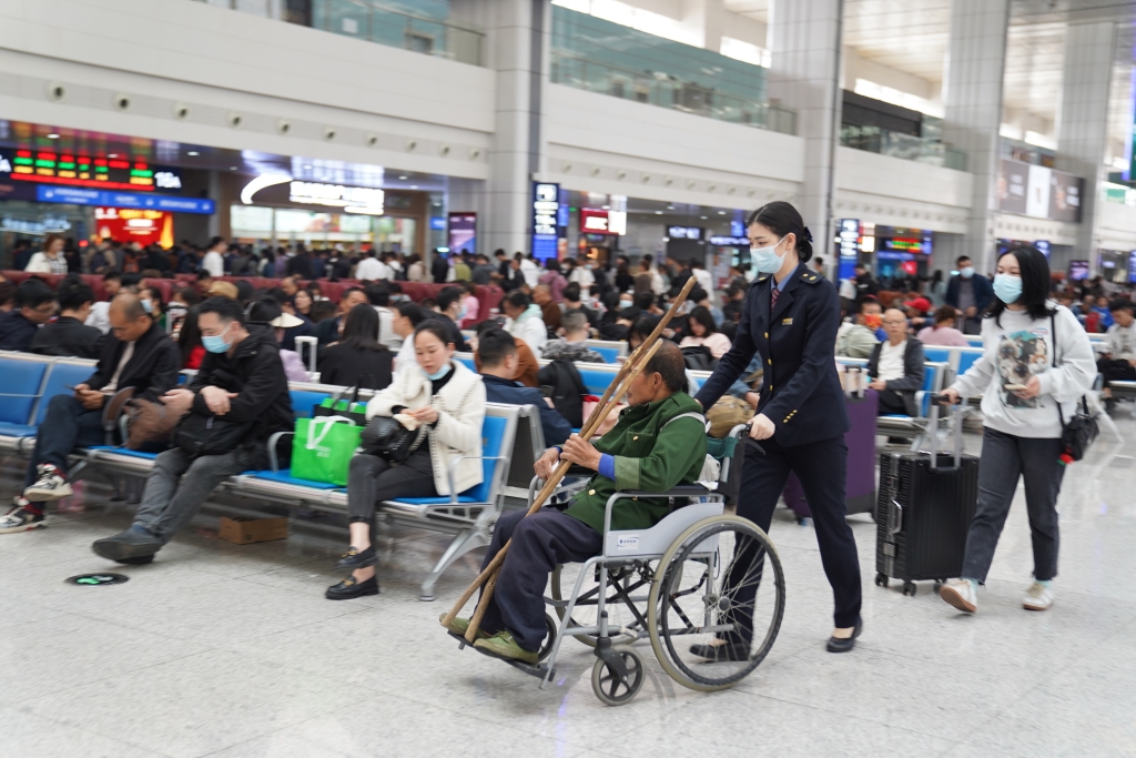 重庆北站“马廉服务台”工作人员正使用轮椅护送重点旅客乘车。通讯员 魏伟 摄