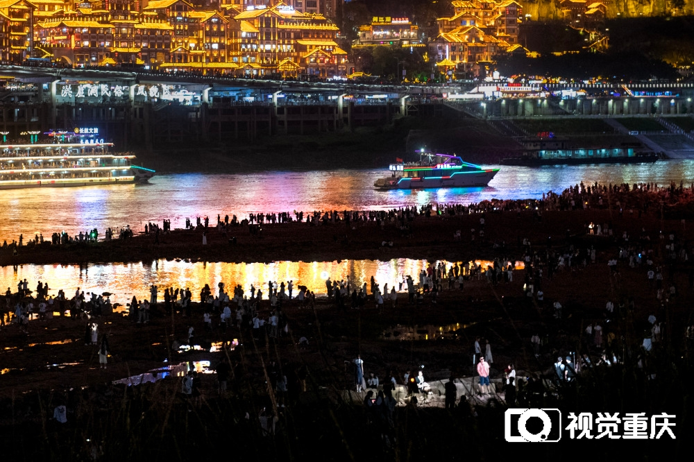 Tourists are standing on the rocky beach in Jiangtan Park, Jiangbeizui, Jiangbei District to enjoy the night view of Hongyadong on April 25. (Photographed by Zhang Jinhui / Visual Chongqing)