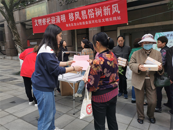 1社区志愿者向过路的居民发放清明文明祭扫倡议书。通讯员 胡琴 摄