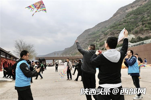 媒体记者在壶口瀑布岸边体验放风筝。2