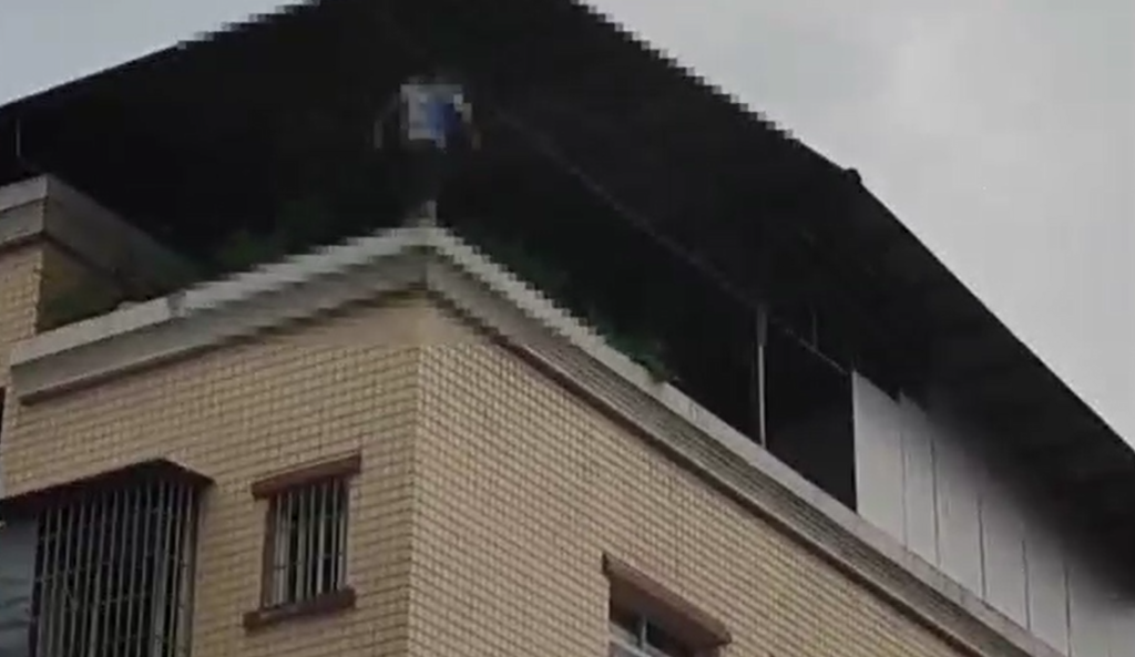 1小伙站在楼顶围墙上,试图轻生。重庆荣昌警方供图