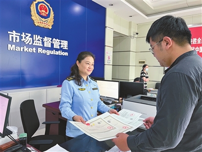 市民吕先生（右）领到开业的证照。记者 张浩 摄