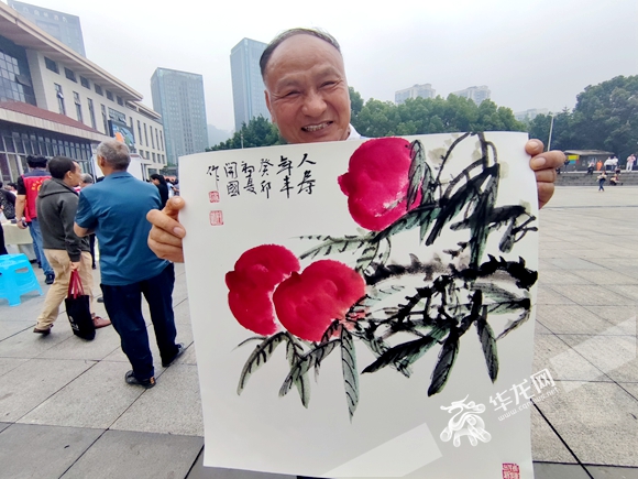 居民展示获赠中国画作品。华龙网-新重庆客户端记者 闫仪 摄