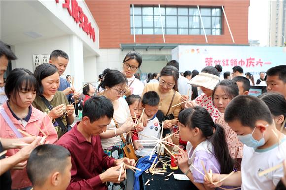 青少年及家长跟着老师一起学习临江棕编的编织技巧。通讯员 陈仕川 摄