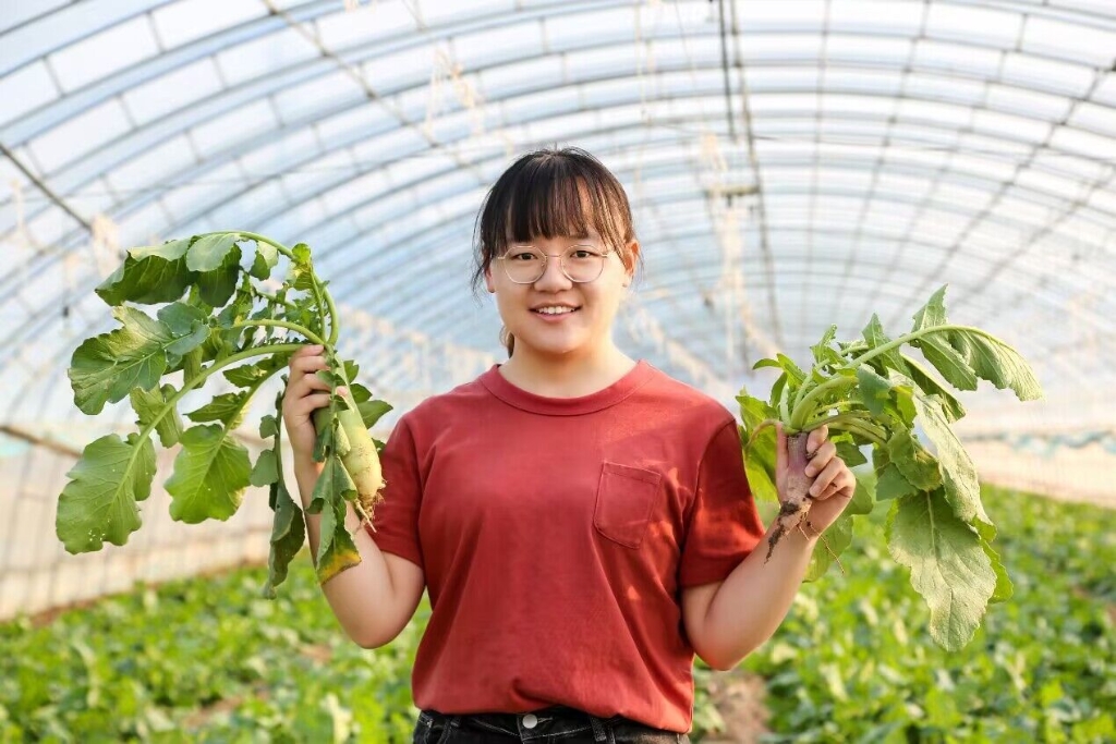张晓恬与她收获的萝卜。 科技小院学生供图华龙网发