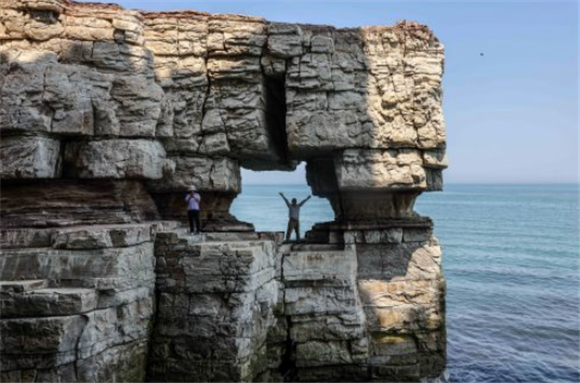 6月15日，游客在海蚀作用形成的“石楼”内游览。新华社记者 朱峥 摄