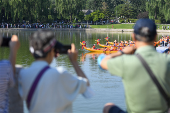 6月22日，游客在北京龙潭湖公园观看龙舟比赛。新华社记者 鞠焕宗 摄