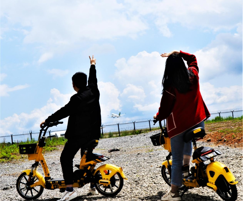 The tourists riding on the Songguo shared an electric bike stop to watch a plane taking off. (Photo provided by the interviewee)