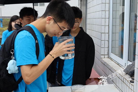 学生雷孟桥拿起烧杯闻净化后的水。华龙网-新重庆客户端 董静 摄