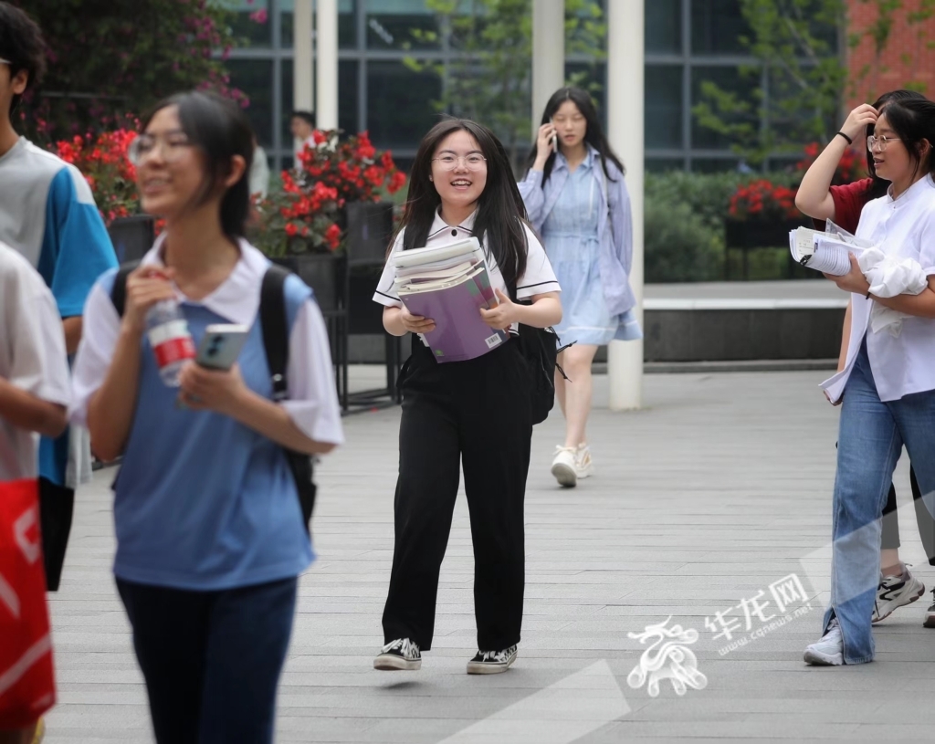 两江新区西南大学附中考点，完成高考的一位考生抱着复习资料开心走出校门。华龙网-新重庆客户端记者 张质 摄