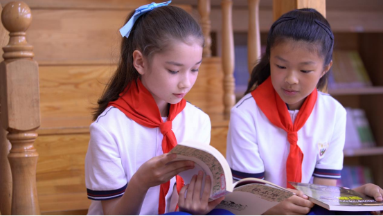 收到儿童节的特殊礼物后，崔媛莹（左）和同学在阅览室读书交流。 通讯员 李雪筝 摄