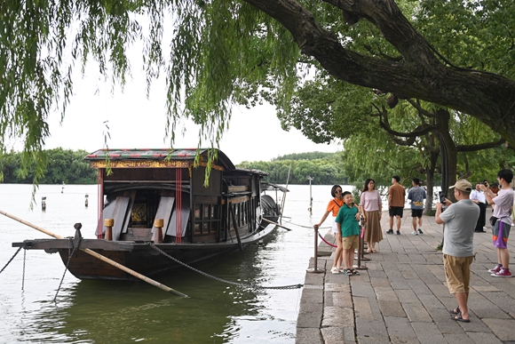 游客在嘉兴南湖红船旁留影。