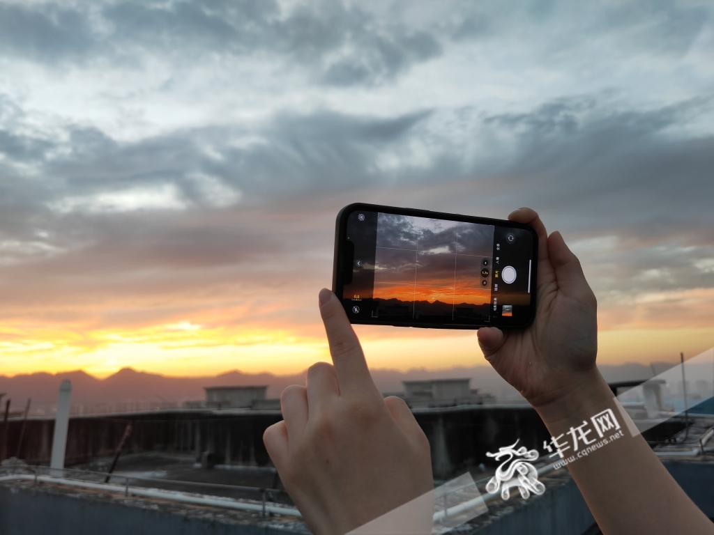 重庆江北，市民拿出手机记录天空的色彩。华龙网-新重庆客户端记者 谢鹏飞 摄