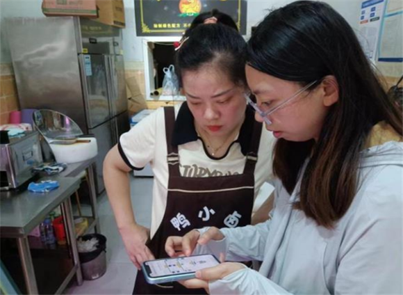 龙凤社区工作人“一对一”开展阳光餐饮APP操作培训。通讯员 黄倩 摄