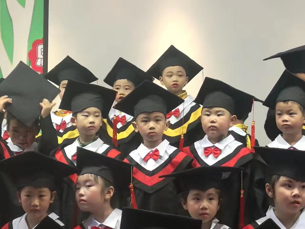 图2:幼儿园小朋友身着“小博士服”准备拍毕业照。
