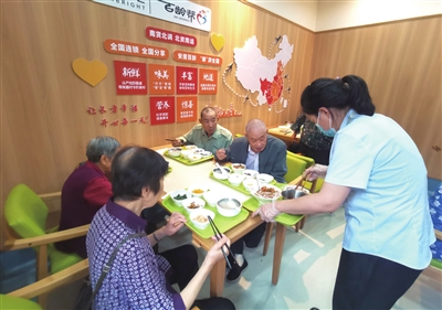梁山街道南华社区老年食堂，工作人员在为老人们加菜。记者 郎兴花 摄