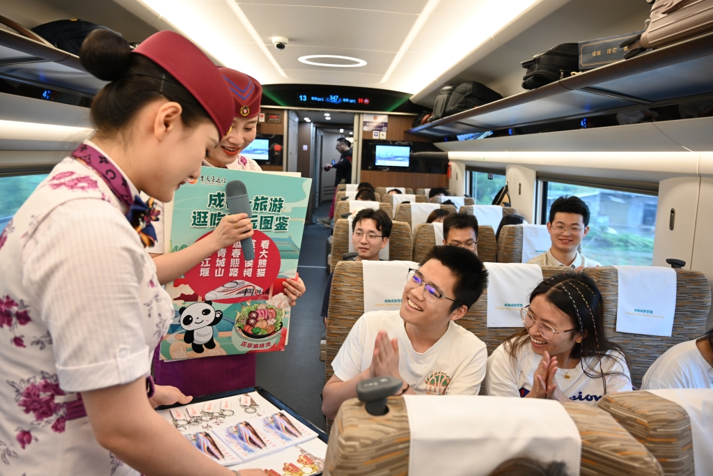 The attendants of the smart Fuxing Chengdu-Chongqing train G8612 hand out gifts to the passengers participating in the activity on July 26. (Photographed by Zhong Jie)