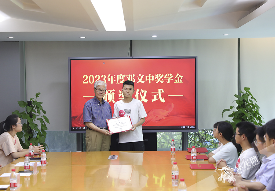 大学新生王佩谦从邓文中院士手中接过获奖证书。华龙网-新重庆客户端 首席记者 李文科 摄