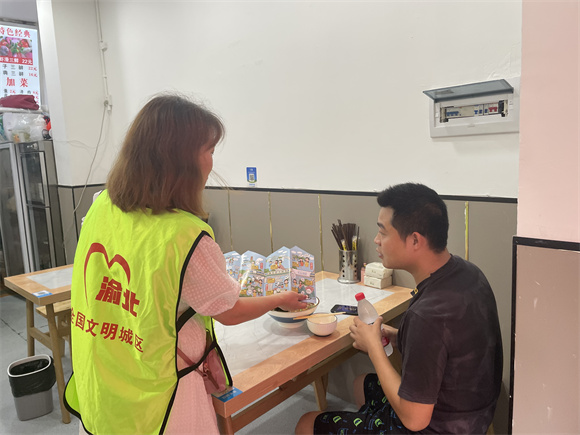 2志愿者向就餐居民宣传“吃得文明·光盘行动”。通讯员 左春燕 摄