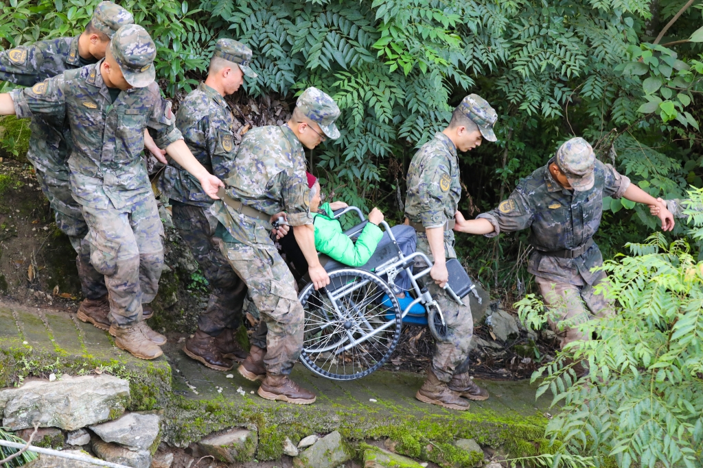 武警官兵抬着瘫痪老人去往山下安置点。通讯员 李东 摄