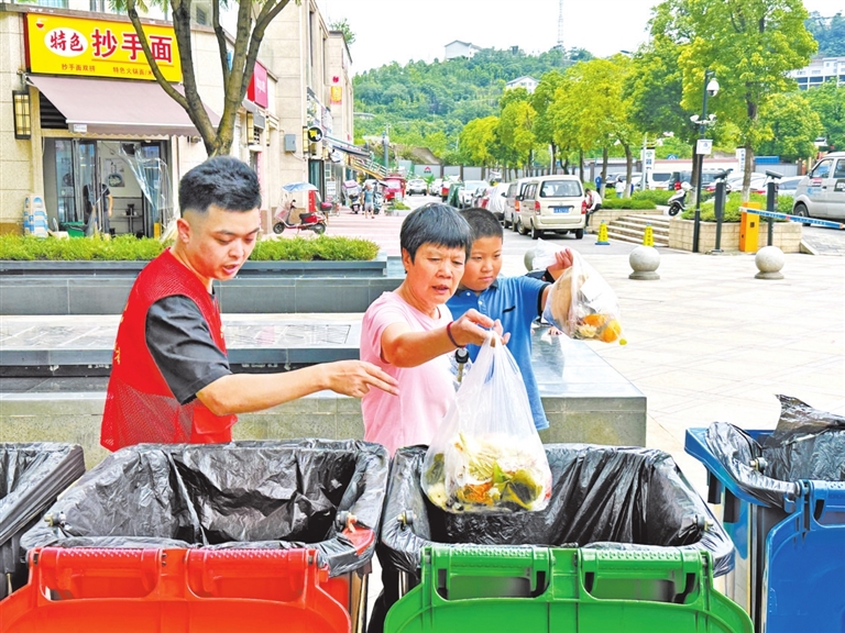 社区工作人员指导居民进行垃圾分类。