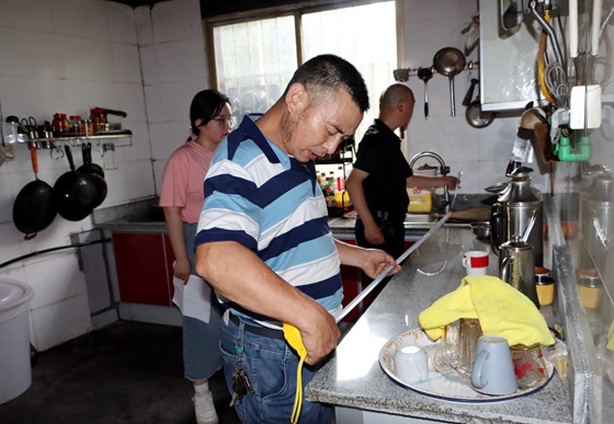 验收组工作人员在测量孙文祥家改造的厨房操作台的长度。特约通讯员 李诗素 摄