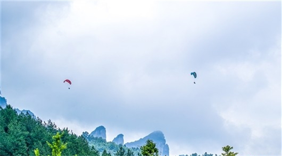 游客在“大金佛山178环山趣驾”游线路上乘坐滑翔伞从空中欣赏世界自然遗产金佛山美景。瞿明斌 摄