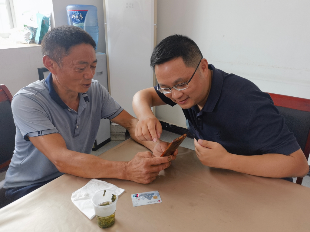 驻村第一书记（右一）喻凯指导村民在重庆农商行手机银行App上申请授信额度