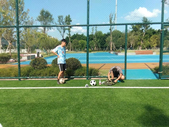 两名少年在绿地环抱的足球场上踢足球。铜梁区城市管理局供图 华龙网发