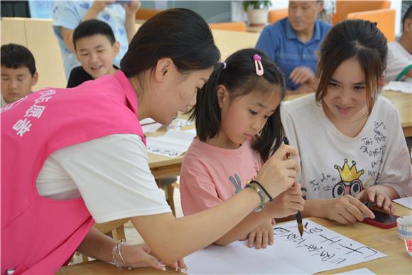 巾帼志愿者指导儿童毛笔控笔方法。  璧山区妇联供图
