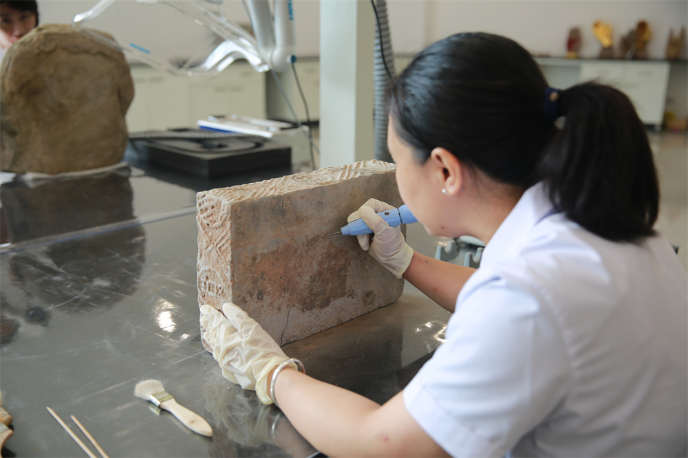大足石刻文物院内，工作人员正在清理文物外壁。大足石刻研究院 供图