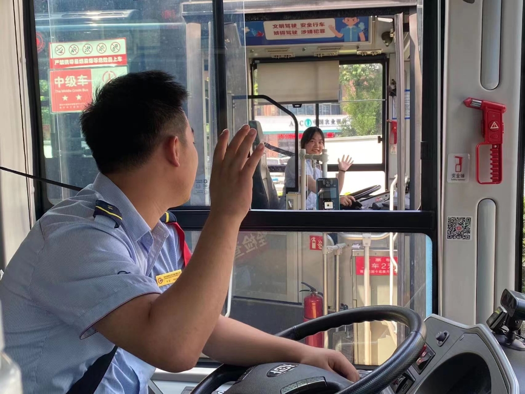 发车前，刘彩霞给等候发车的丈夫打招呼。重庆南部公交供图