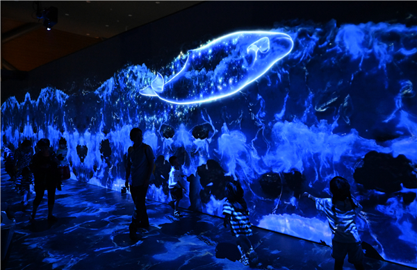 在数字技术支撑下，游客在国家海洋博物馆“鲸奇物语”展区与虚拟海洋生物互动。新华社记者 孙凡越 摄