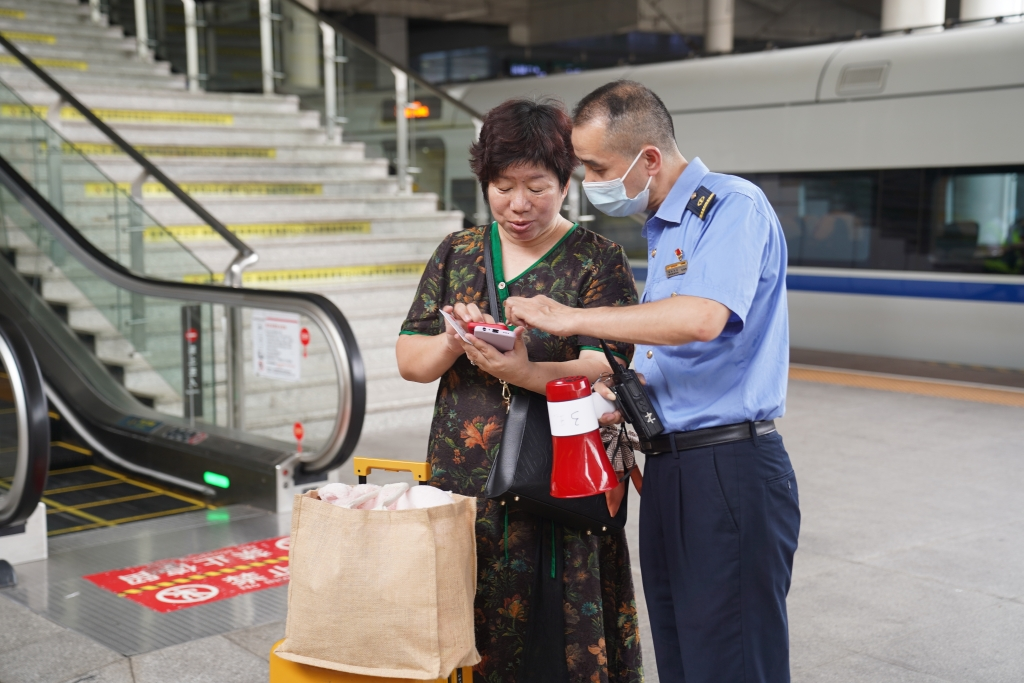 On the platform in Chongqingbei Railway Station, a staff helping a passenger check the train information. (Photographed by Wang Liang)