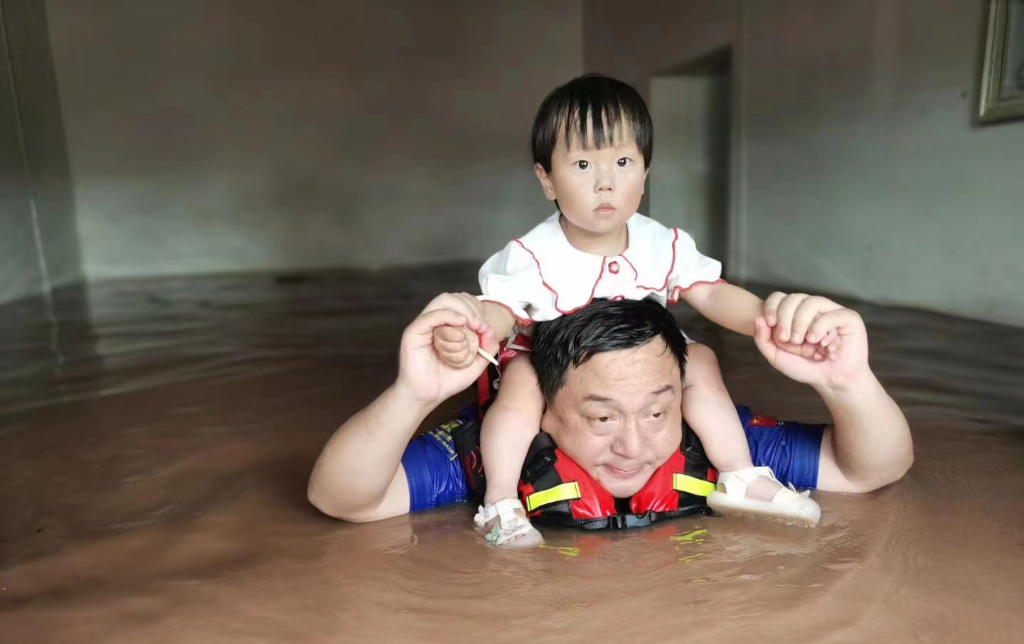 蓝天救援队队员在洪水中托举小孩子。潼南区委宣传部供图  华龙网发