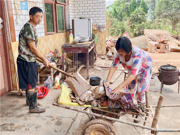 夏康夫妇俩帮助村民清理院落。潼南区委宣传部供图   华龙网发