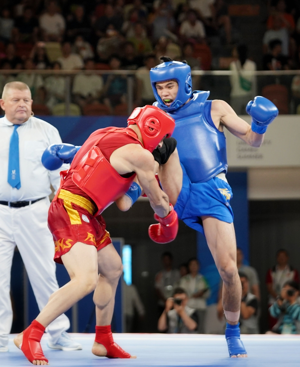 He Feng (in blue) beats an Iran athlete and claims gold in the men’s Sanda 70kg final.