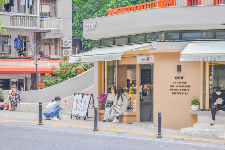 市民在民主村一间咖啡馆门前休息、拍照。记者 曹鸣鸥 摄