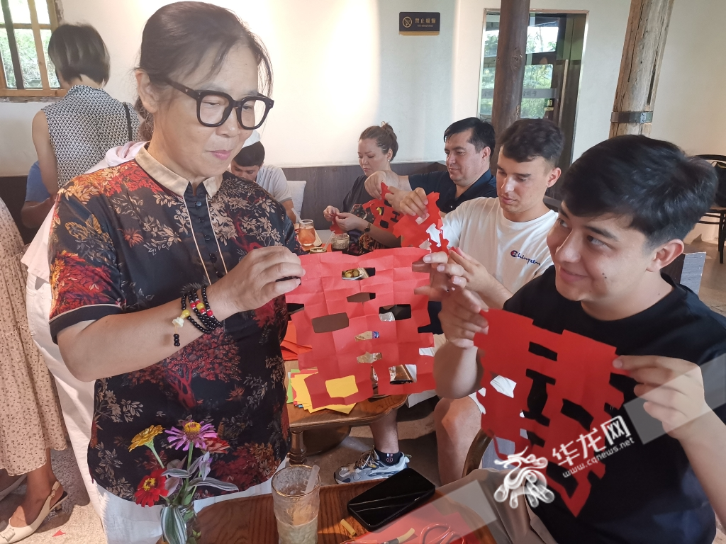 Youth representatives from five Central Asia countries experiencing the paper-cut intangible cultural heritage in Jingangbei Ancient Village under the guidance of two Chongqing arts and crafts masters