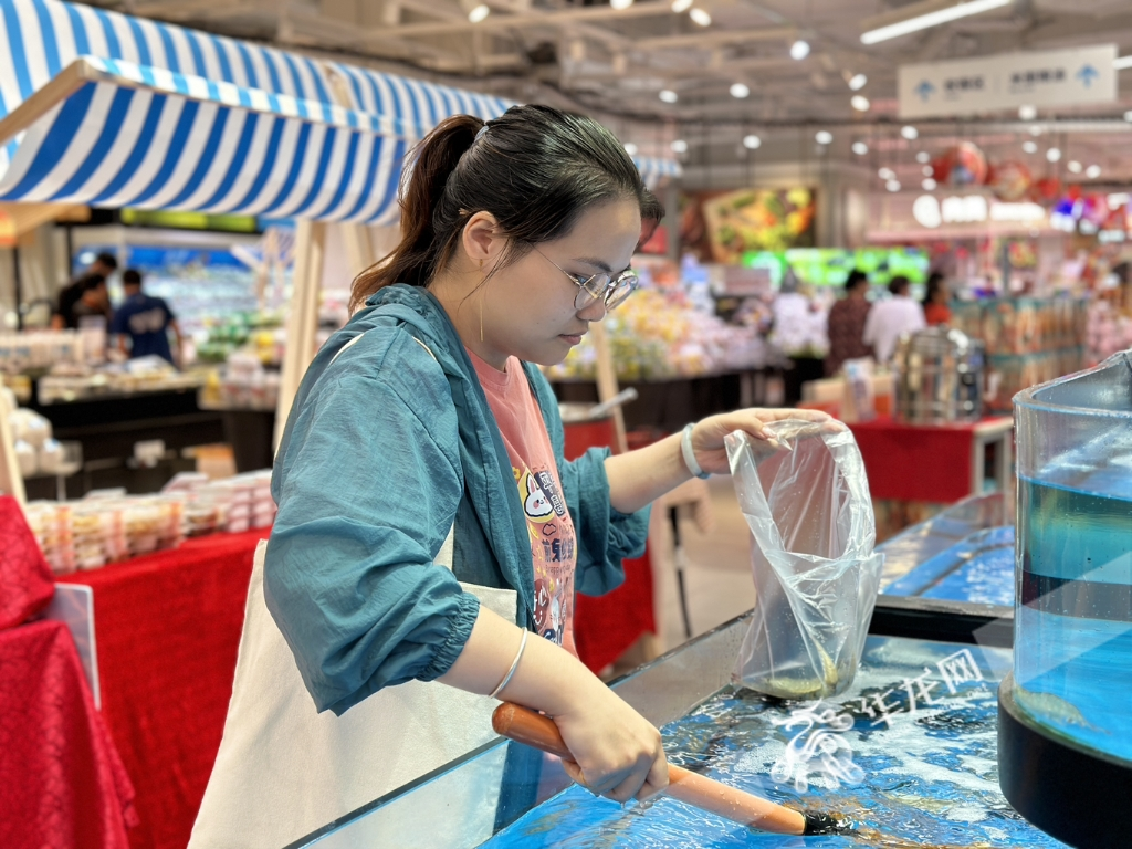 A consumer picking up live shrimps at a Freshippo store.