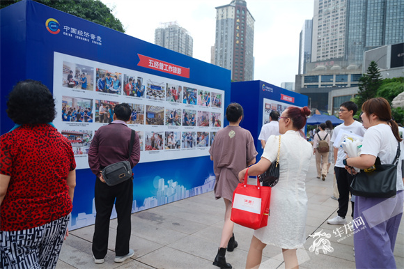 观音桥路过的市民们正在围观五经普掠影展板内容 华龙网 董悠 摄