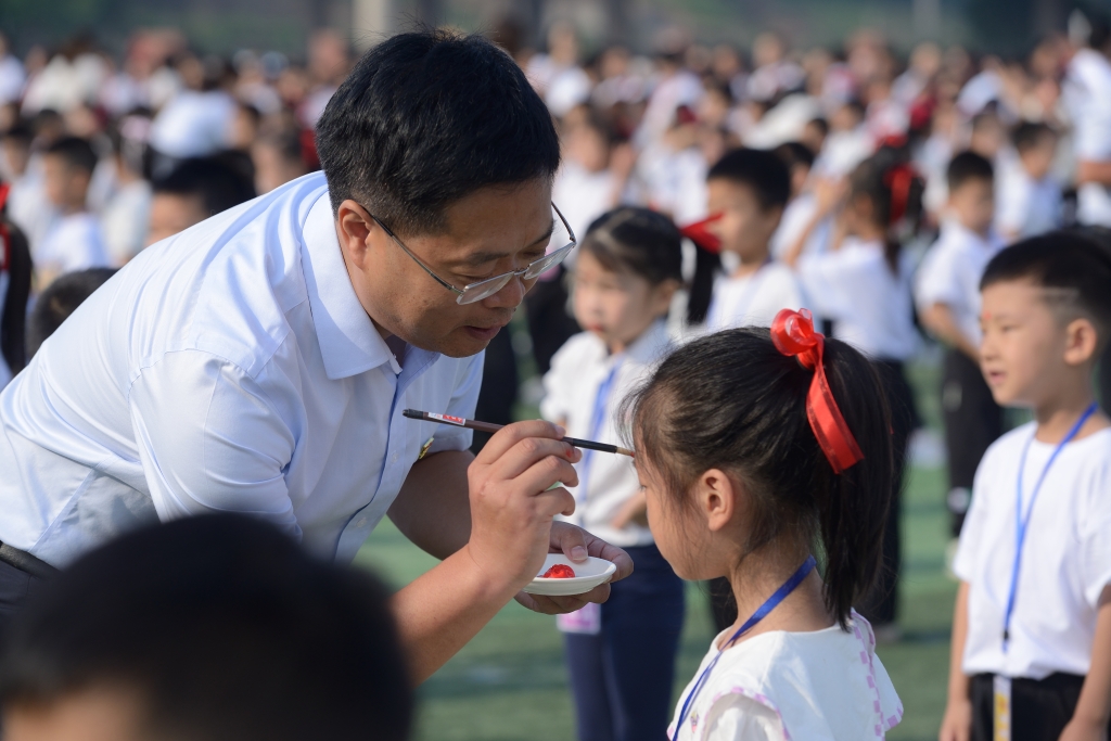 五洲小学校长殷帮强向一年级学生点朱砂，启智慧。