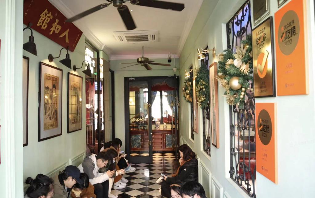元旦假期，上海“必吃榜”餐厅人和馆门口坐着排着等位的顾客。受访者供图