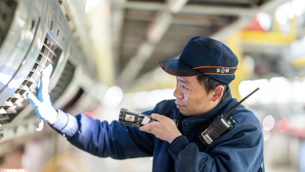 重庆车辆段重庆西动车运用车间班组职工在对动车组两侧裙板进行检修。