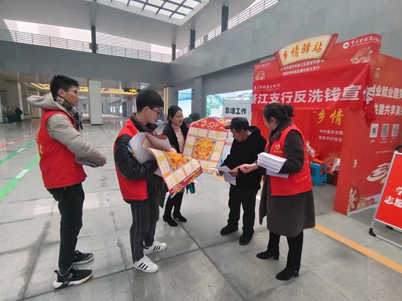 志愿者在綦江东站向返乡群众发放年画