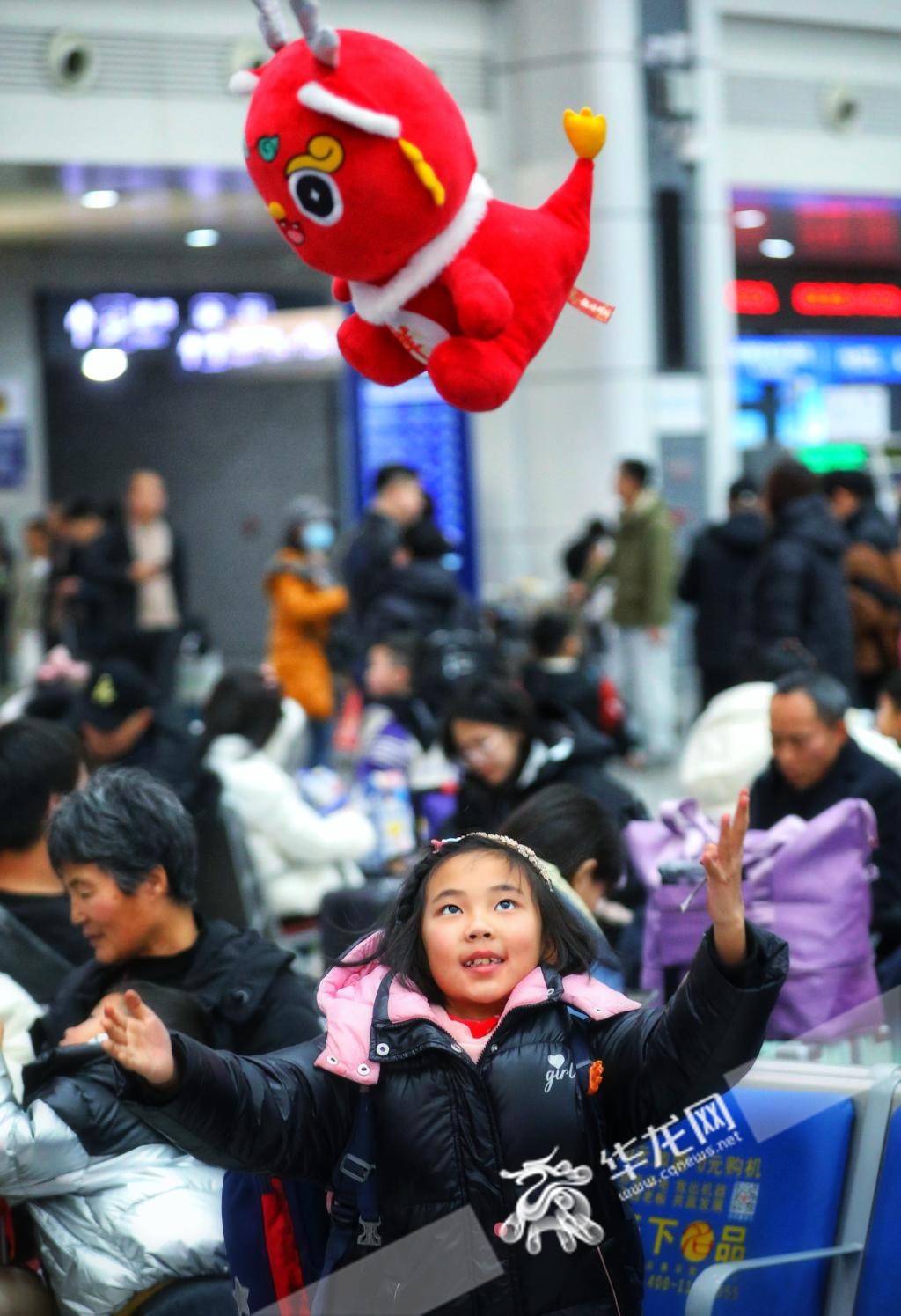 04，小女孩张张在候车大厅抛玩着红色的布绒龙宝宝，她和弟弟、婆婆乘车回四川资阳过年。