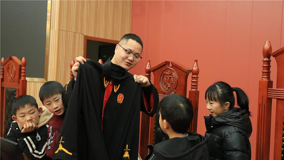 审判长正向孩子们展示法袍。通讯员 刘馨 摄