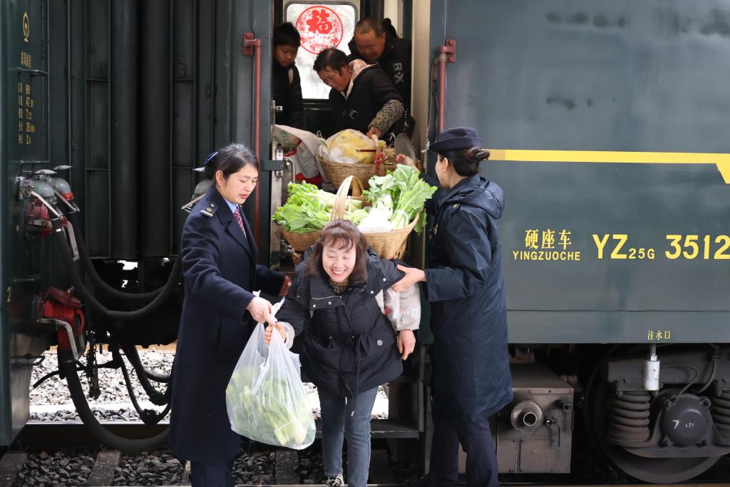 列车工作人员帮助菜农下车。