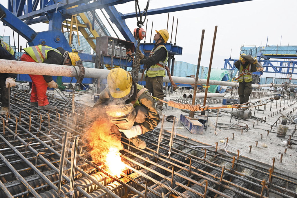 Luo Xiaobo welding reinforcing bars on the cantilever girders of the bridge deck which is 105 meters high from the ground