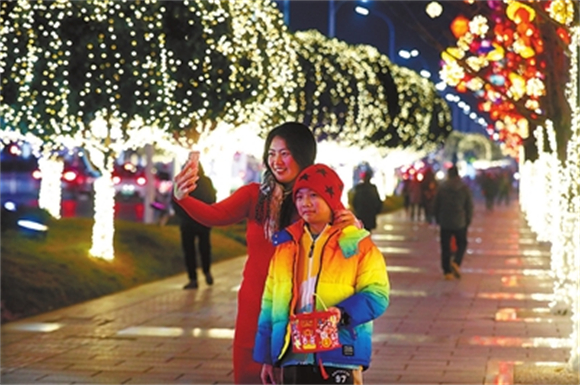 双桂城区桂西路，市民带着孩子欣赏美丽的灯饰夜景，拍照打卡。记者 向成国 摄